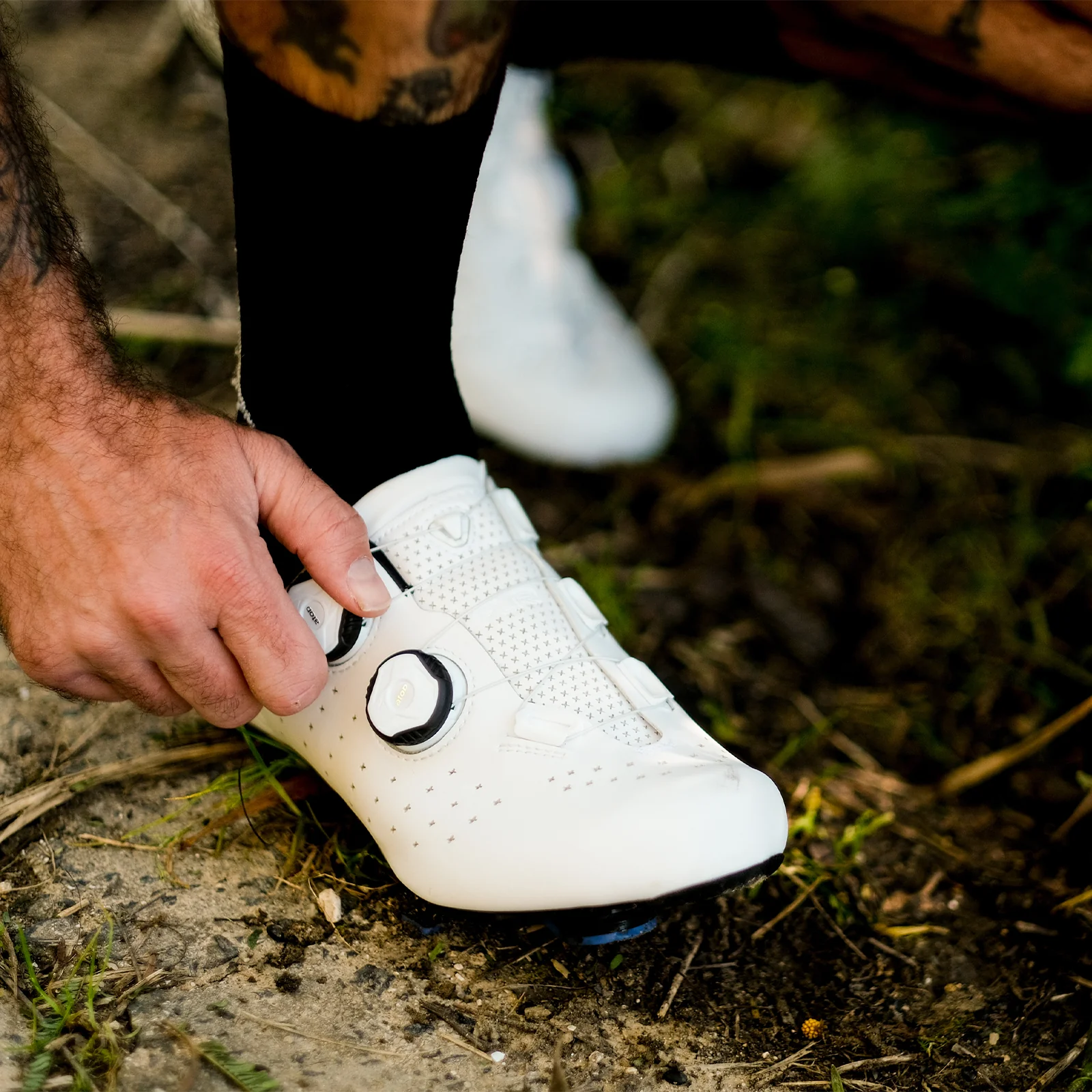Rider adjusting the fit of a white FLR F-9 cycling shoe
